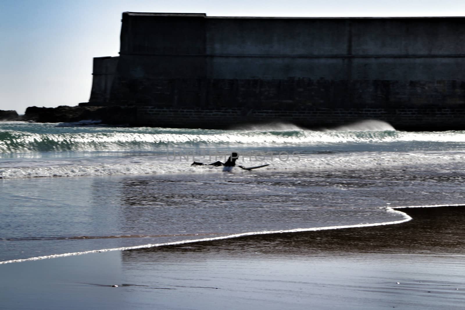 Beautiful beach called Praia da Torre in Lisbon, Portugal, in a sunny day of Spring. Surfers playing with the waves.