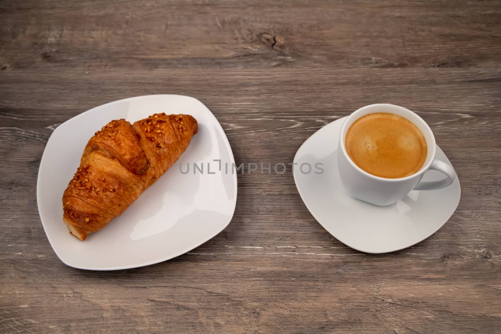 The breakfast with a delicious croissant on a plate and a coffee