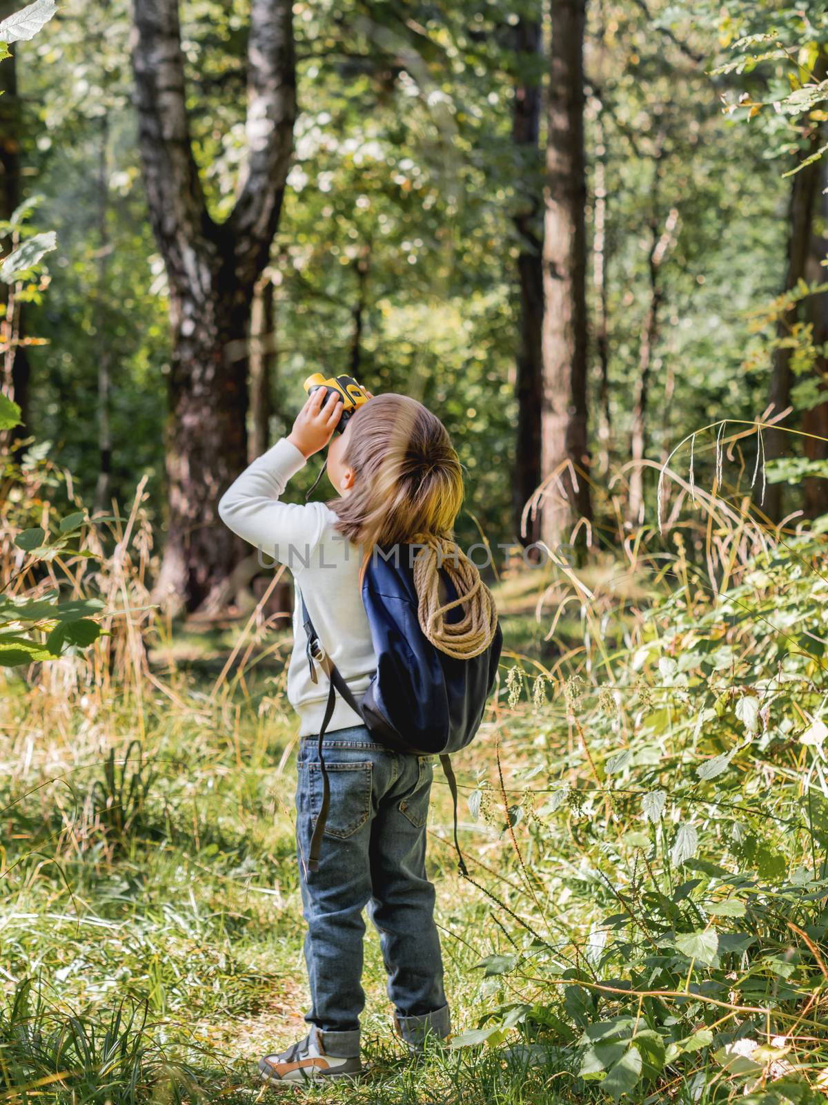 Curious boy is hiking in forest. Outdoor leisure activity for ki by aksenovko