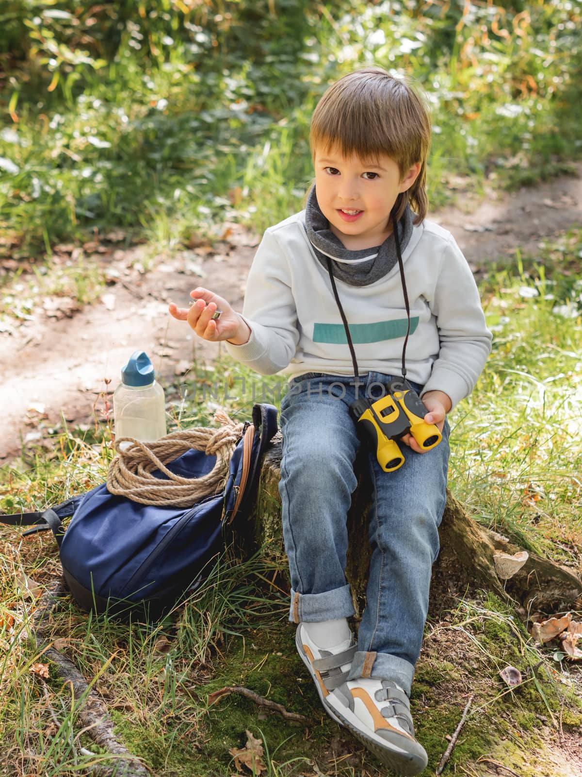 Little explorer on hike in forest. Boy with binoculars and compa by aksenovko