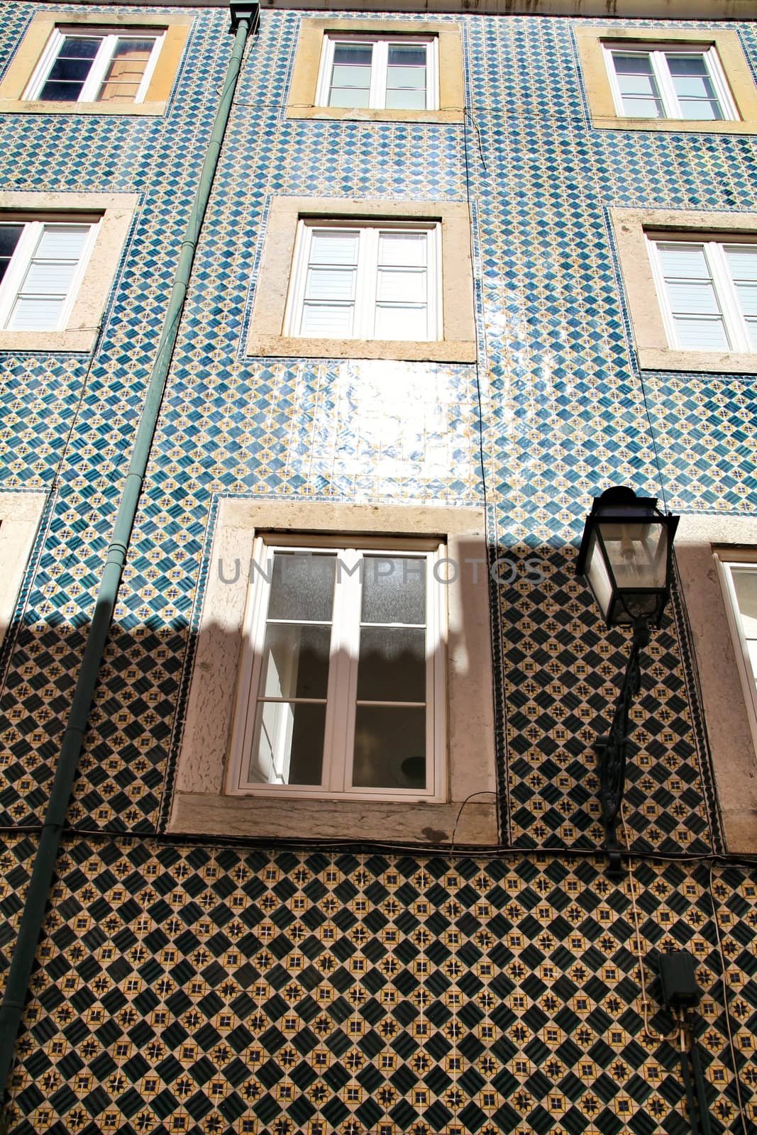 Old colorful and majestic tiled facades with vintage streetlight in Lisbon streets in Spring.