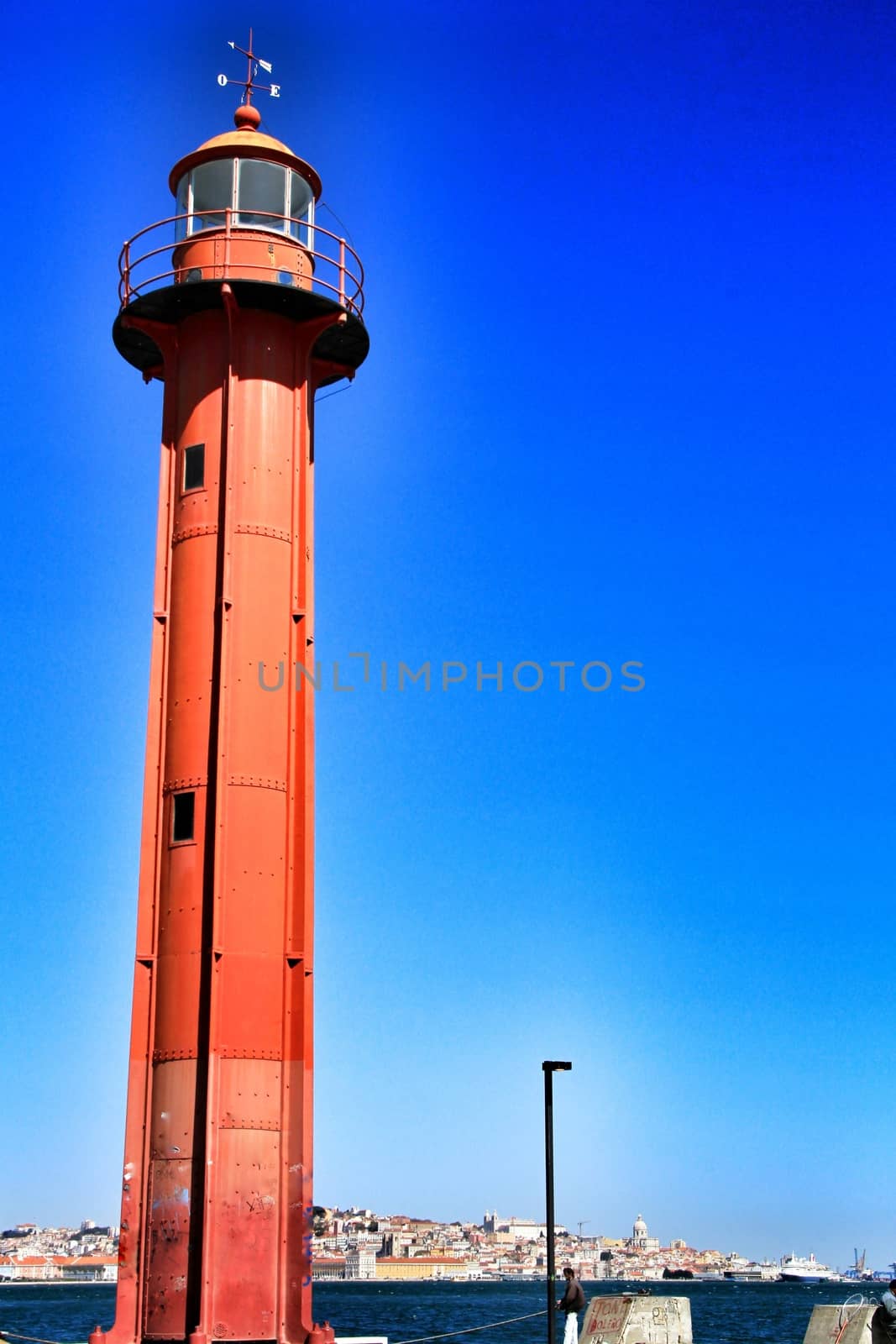 Red lighthouse in the port of Almada village in Lisbon on a sunny day of winter. 