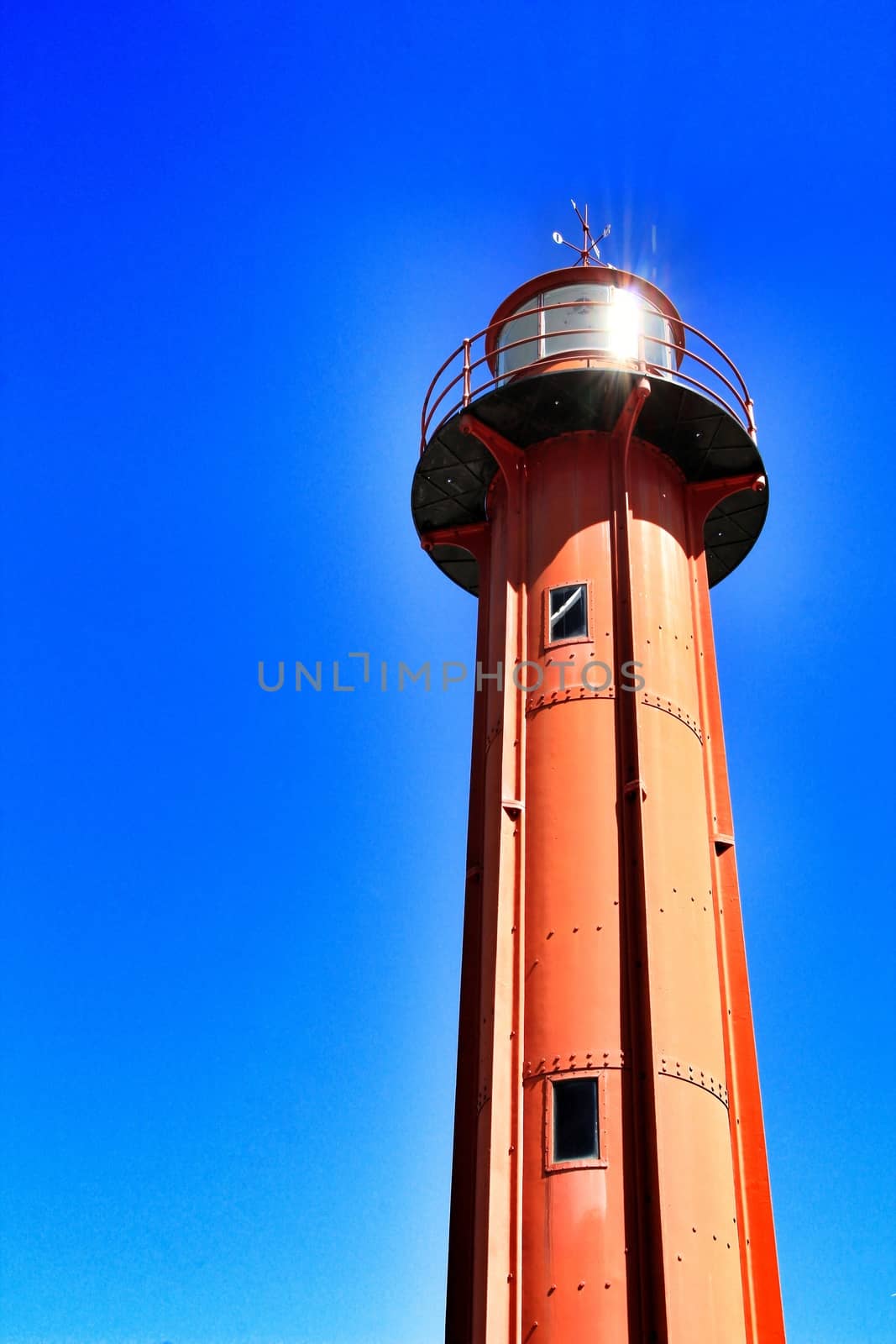 Red lighthouse in the port of Almada village in Lisbon on a sunny day of winter. 
