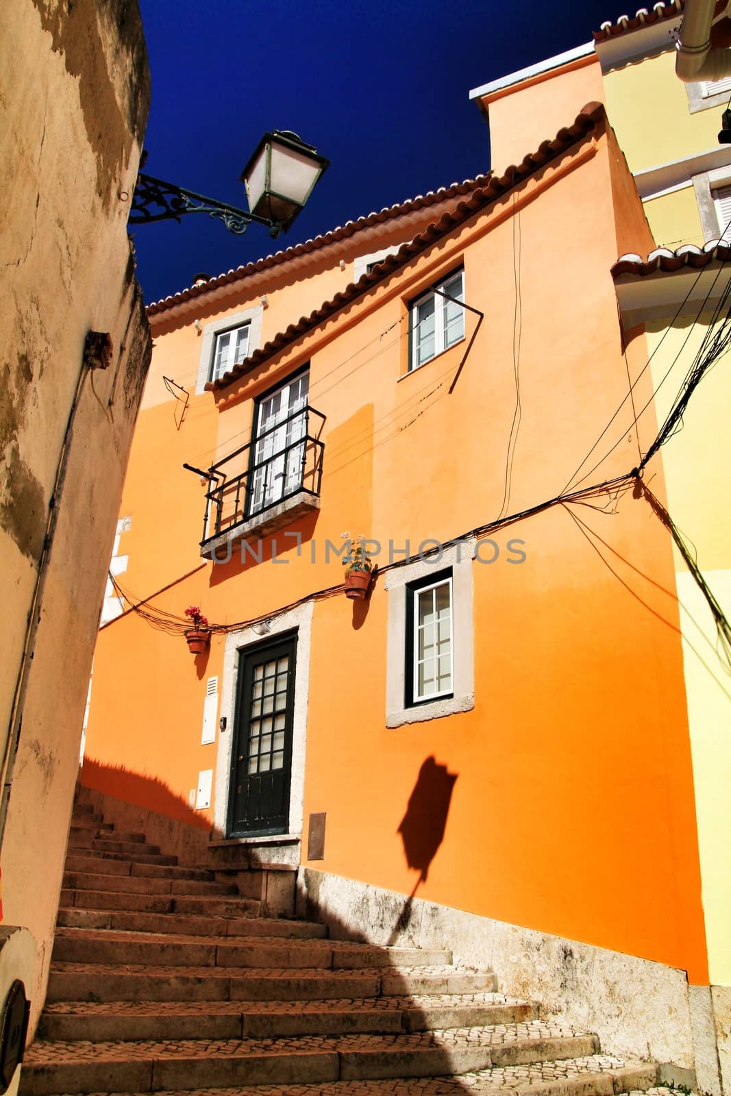 Old colorful and beautiful facades with vintage streetlight in Lisbon streets in Spring. Clothesline in the facade with hanging clothes