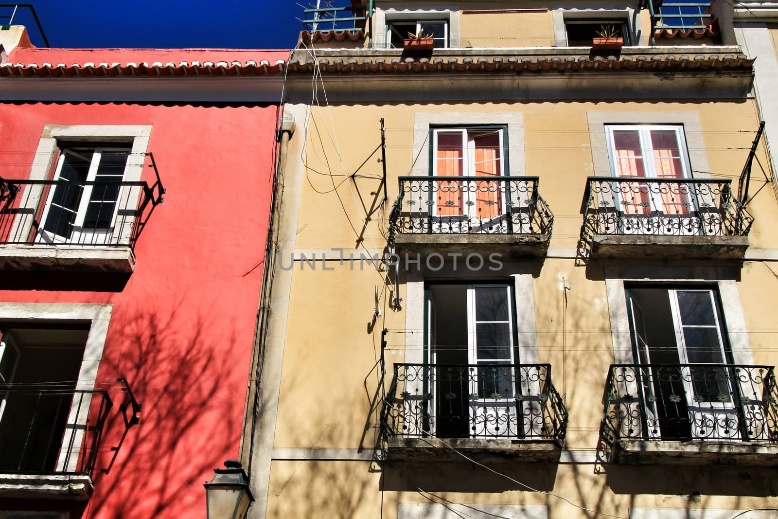 Old colorful and beautiful facades with vintage streetlight in Lisbon streets in Spring. Clothesline in the facade with hanging clothes