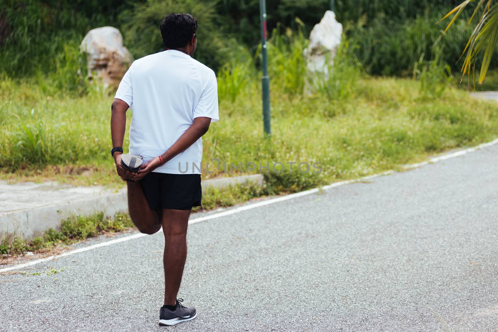 Close up Asian young athlete sport runner black man wear watch lift feet stretching legs and knee before running at the outdoor street health park, healthy exercise before workout concept