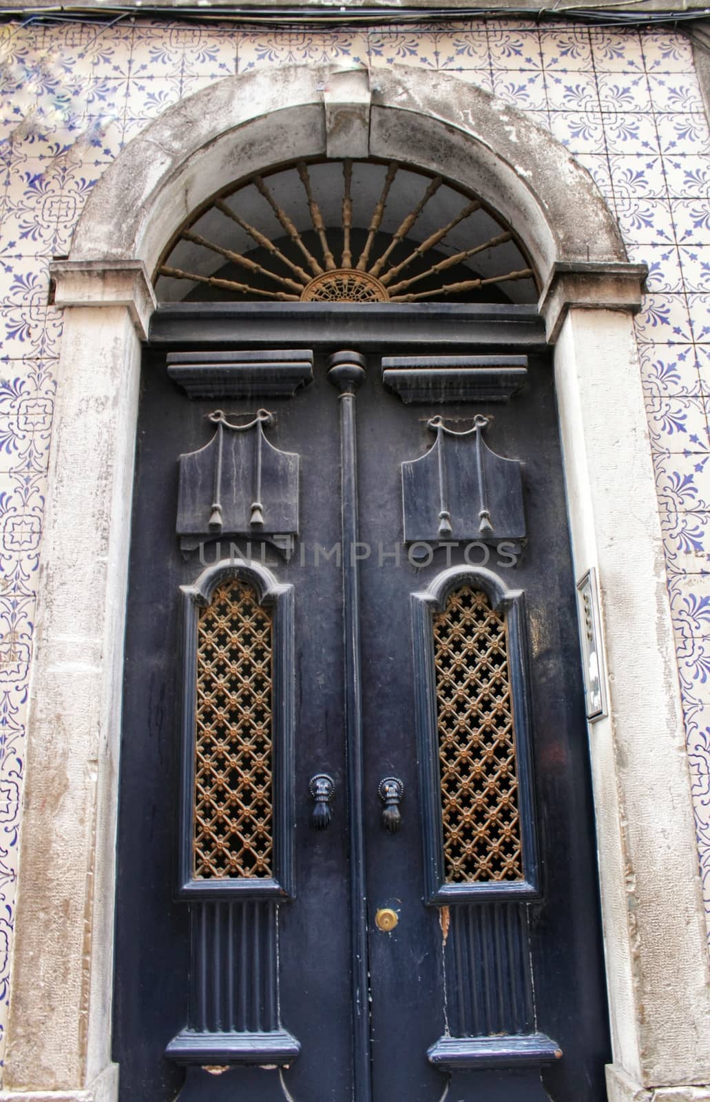 Old wooden door in Lisbon. Wrought metal details on the door.