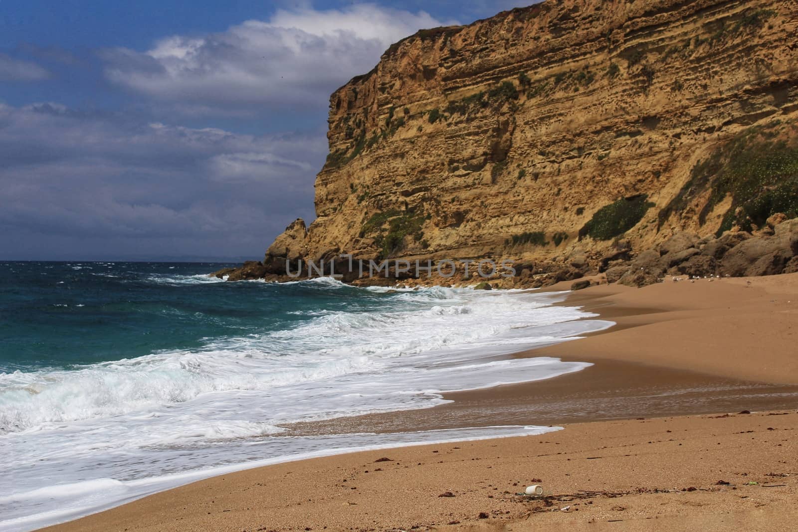 Crystal clear and wild waters in Praia da Foz, Sesimbra, Portugal. Golden sand , seagulls flying, Cliffs and rock formation