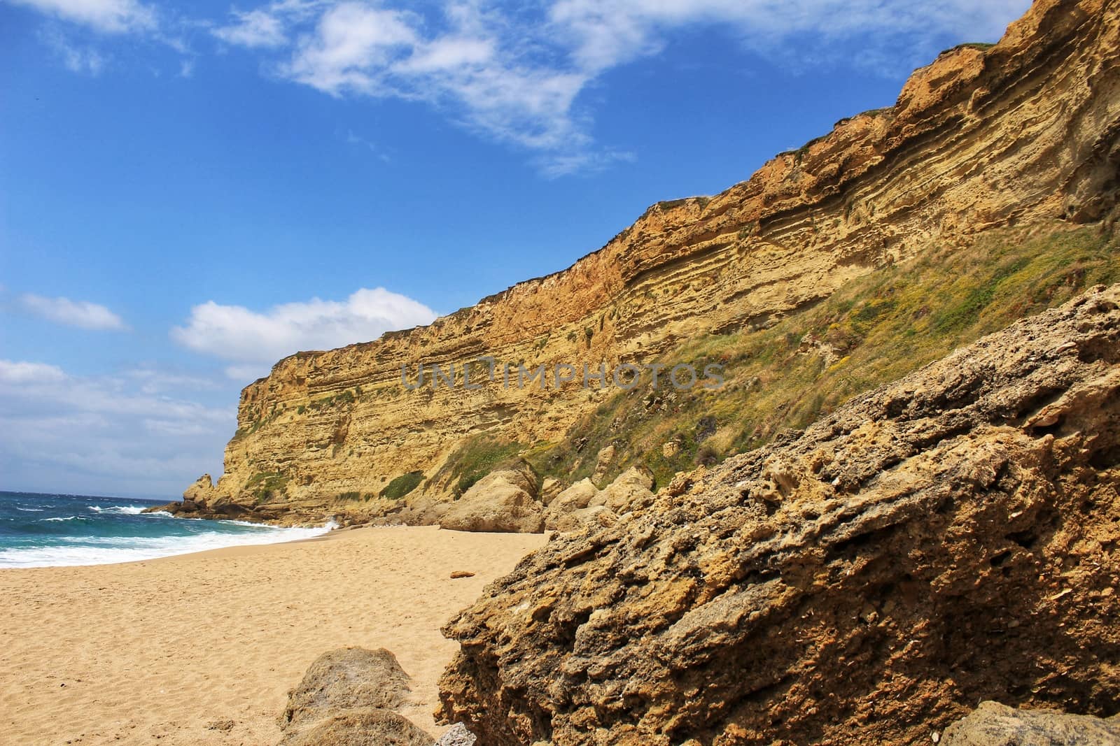 Crystal clear and wild waters in Praia da Foz, Sesimbra, Portugal. Golden sand , seagulls flying, Cliffs and rock formation