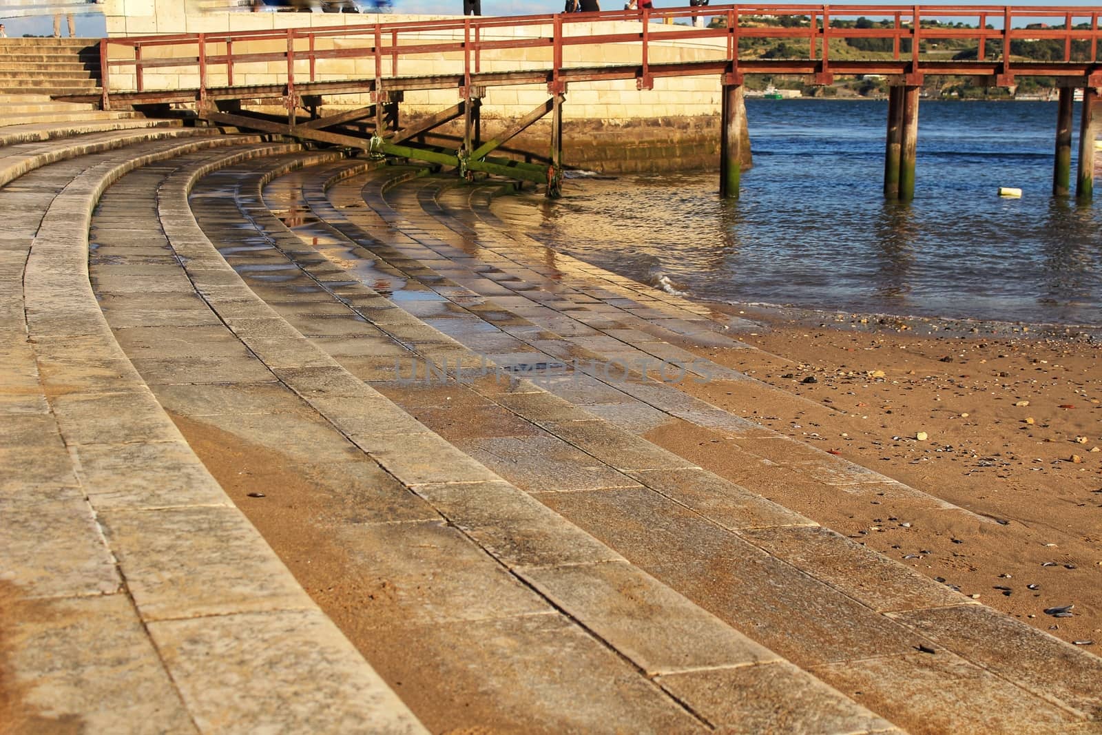 Staircase of Belem tower and quiet Tagus river water in Lisbon under blue sky in the afternoon.