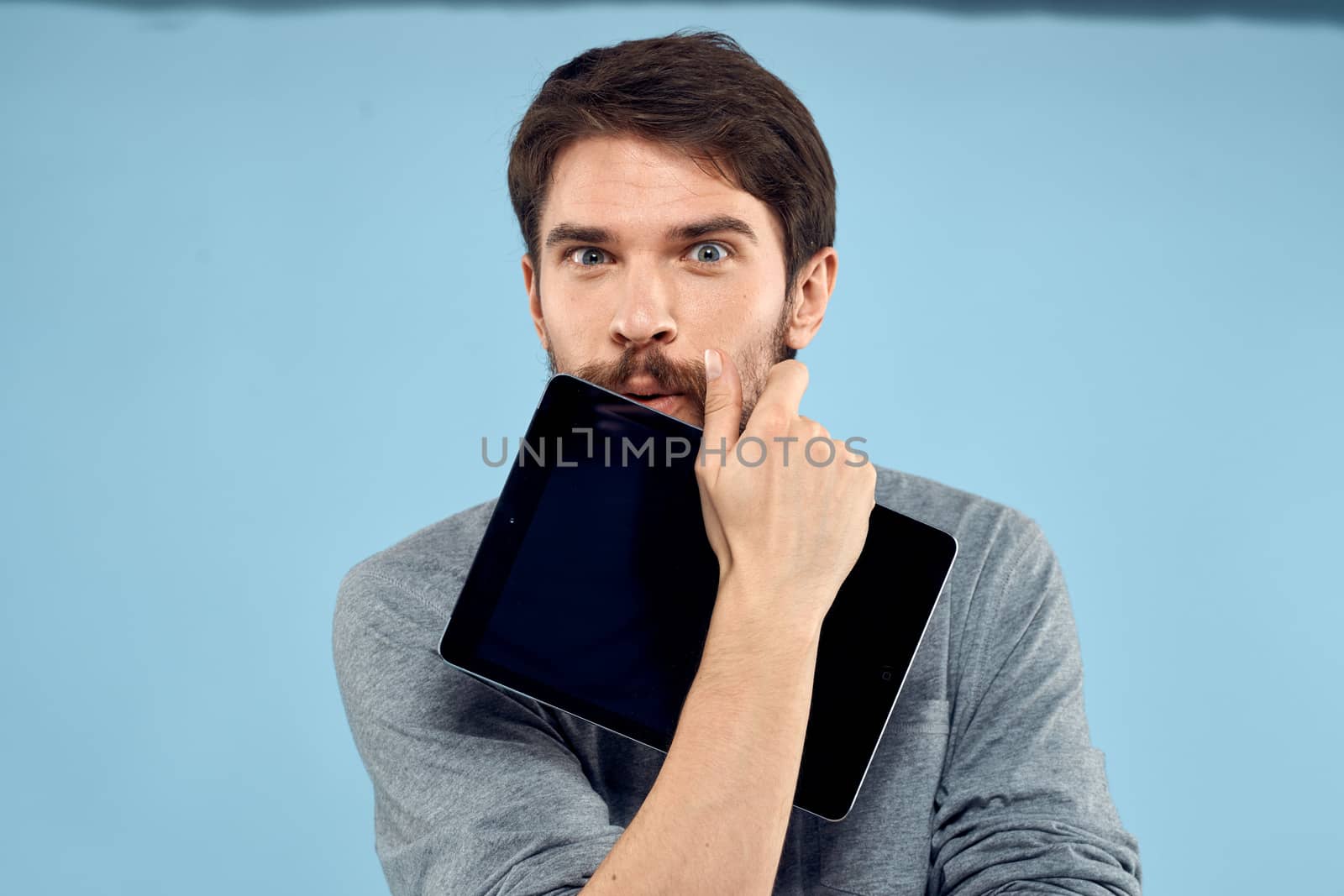 Emotional man with a tablet in the hands of a wireless device internet technology lifestyle blue background. High quality photo