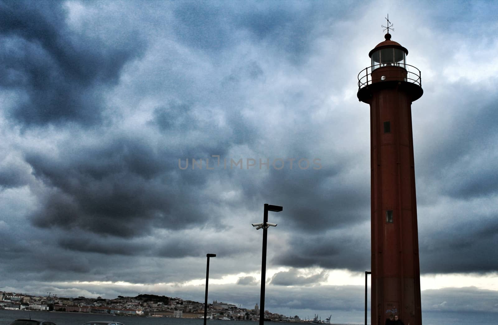 Red lighthouse in the port of Cacilhas village in Lisbon on a gray and cloudy day