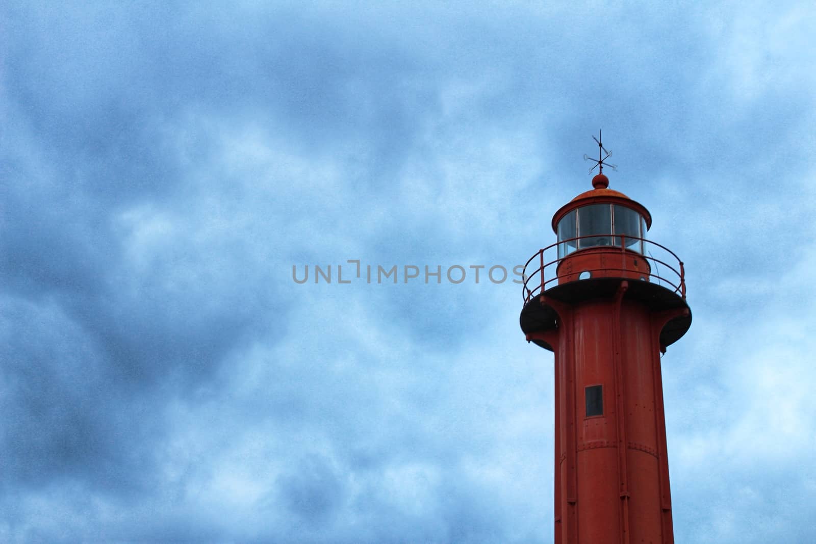 Red lighthouse in the port of Cacilhas village in Lisbon on a gray and cloudy day