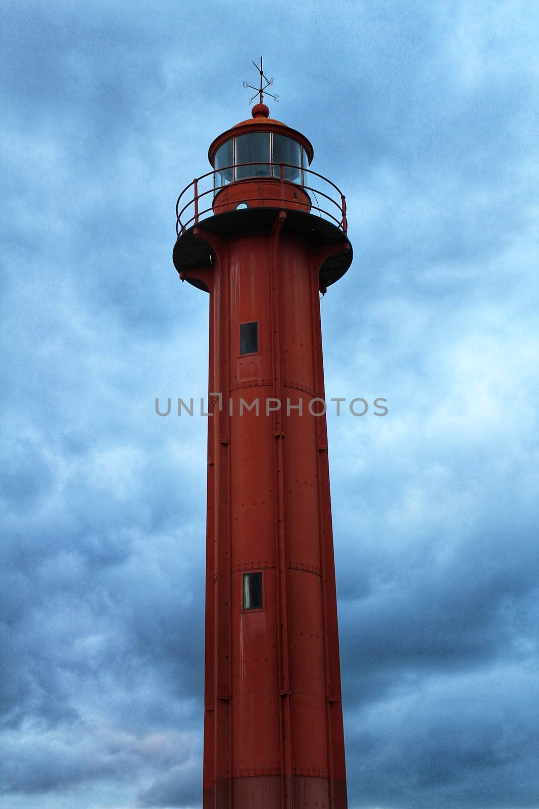 Red lighthouse in the port of Cacilhas village in Lisbon on a gray and cloudy day