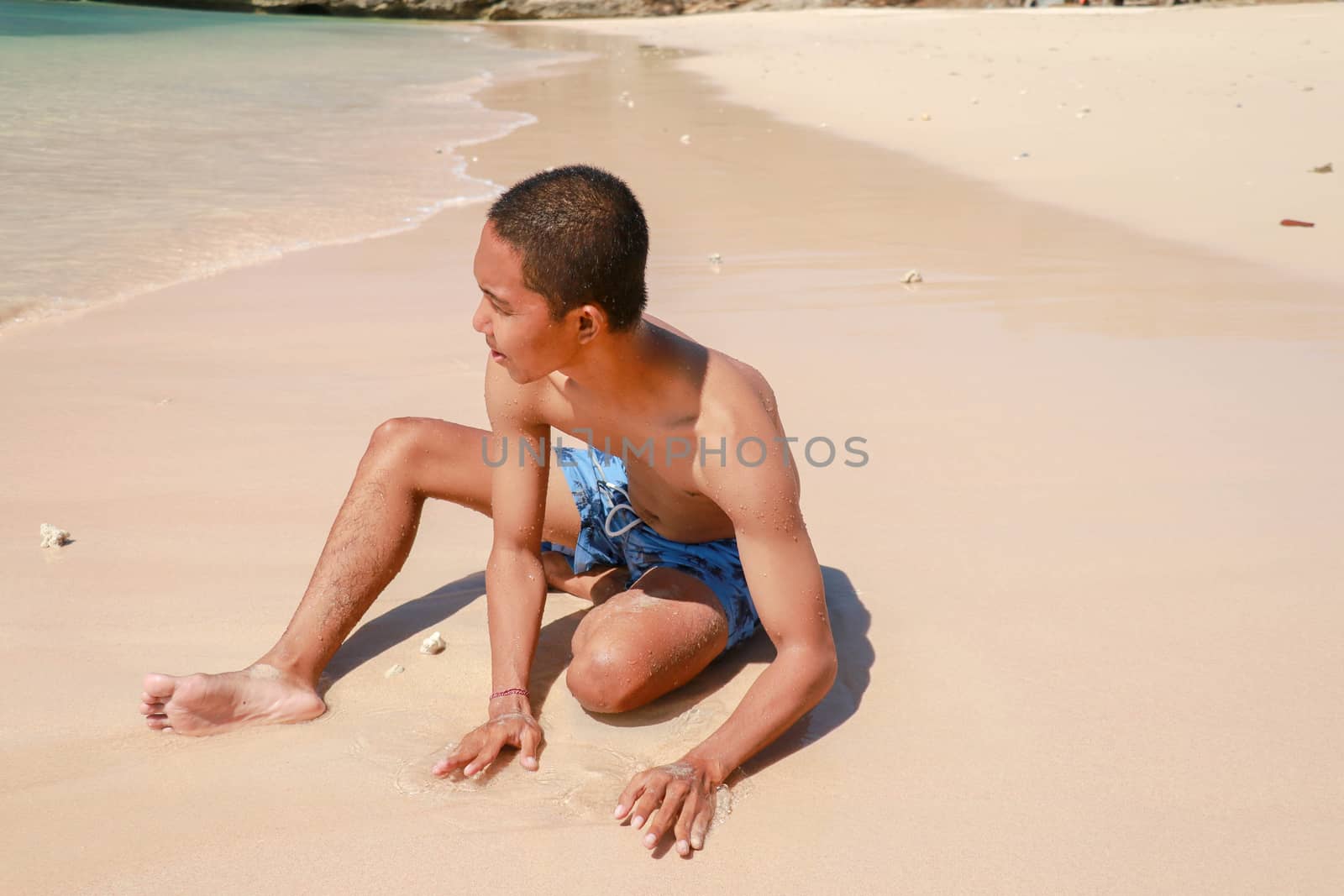 Tourist handsome man sitting and enjoying the view on the tropical beach. Summer concept.