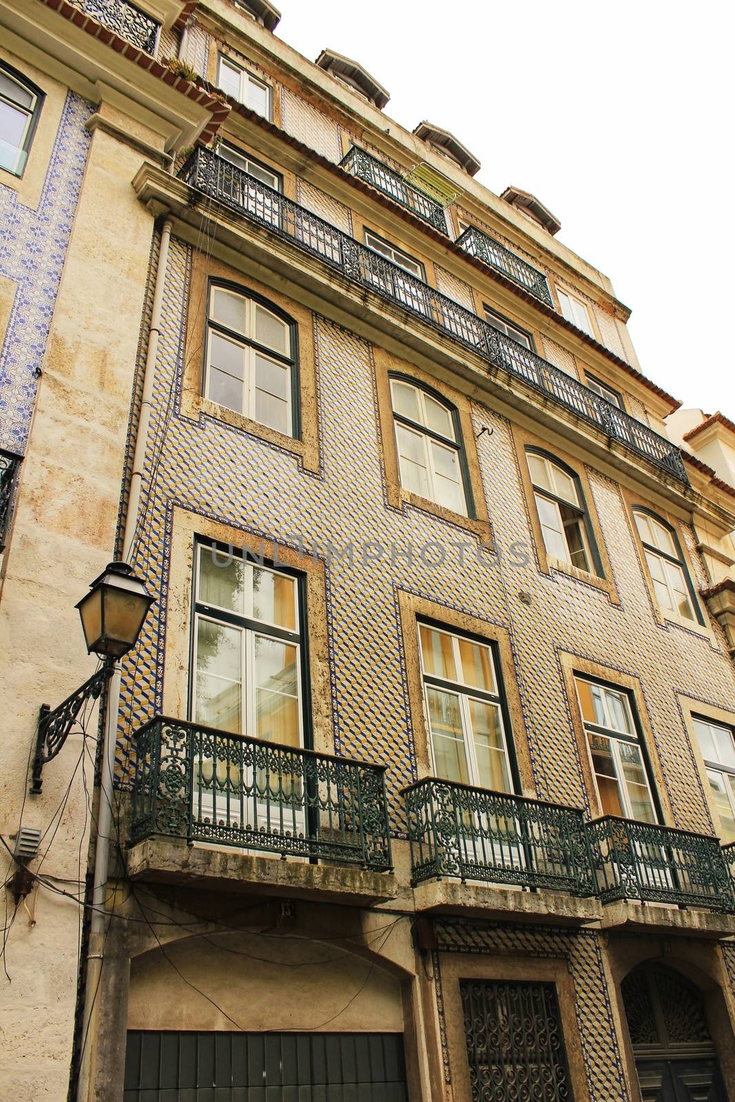 Old and colorful facade in Lisbon with plants and vintage lantern