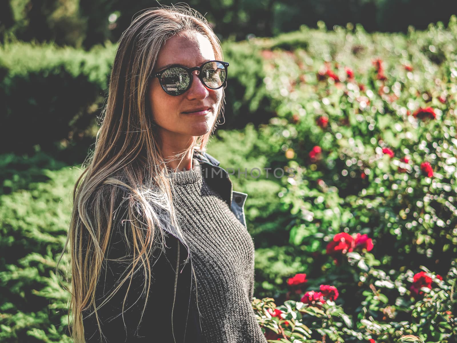 Photo of caucasian Pretty young girl while walking outdoor through field with flowers. Woman with long hair and dark coat in nature. autumn in Estonia. Green backgroun. Copy space