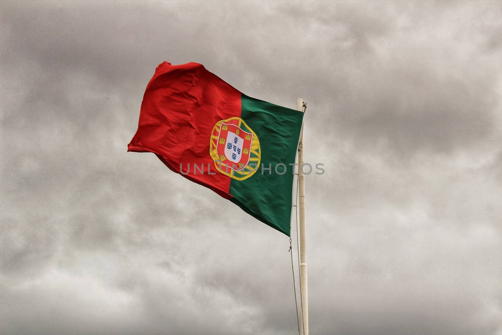 Portugal flag waving under cloudy sky in Lisbon