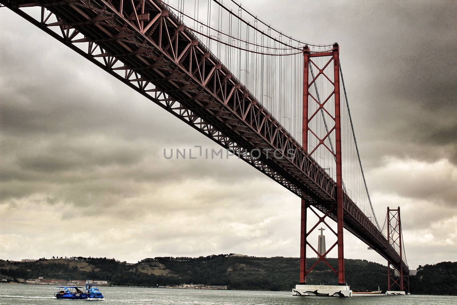Lisbon, Portugal- June 1, 2018:Banks of the river Tagus in Lisbon in Spring on a cloudy day. Beautiful 25th April bridge structure.