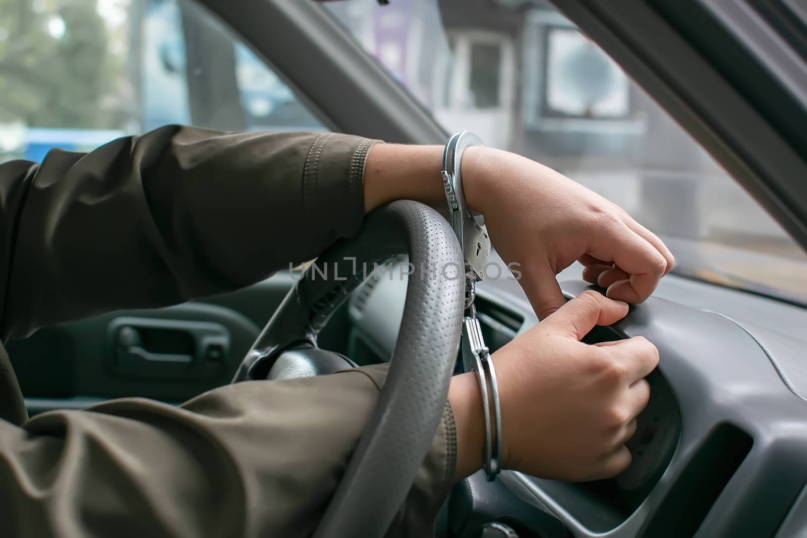 hands of a person, a car driver, handcuffed to the steering wheel, arrest of a criminal