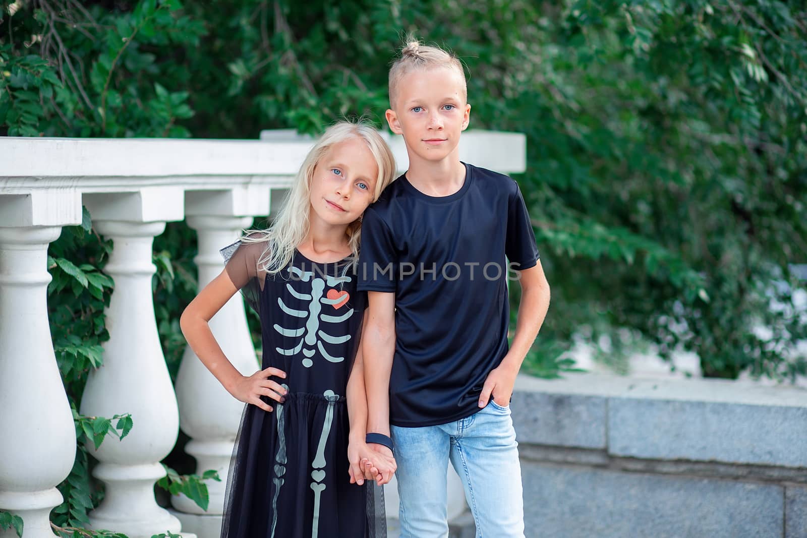 Modern children. Brother and sister in black fashionable clothes stand by the handle. Skeleton pattern on halloween dress