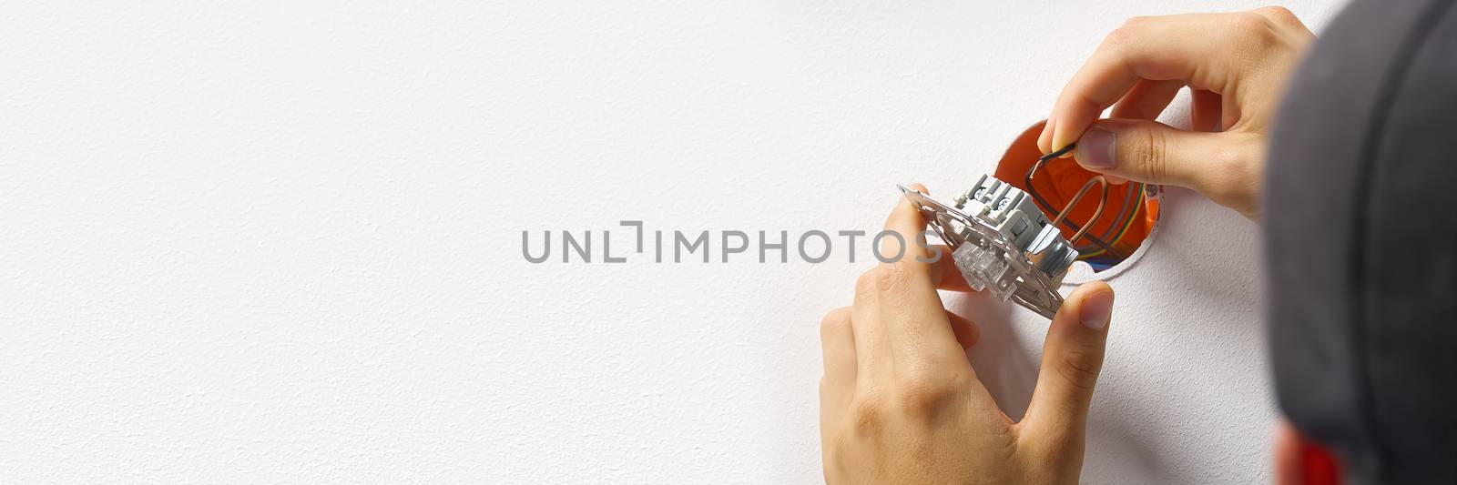 electrician installing light switch on painted wall with screwdriver. Man installing light switch after home renovation. by PhotoTime