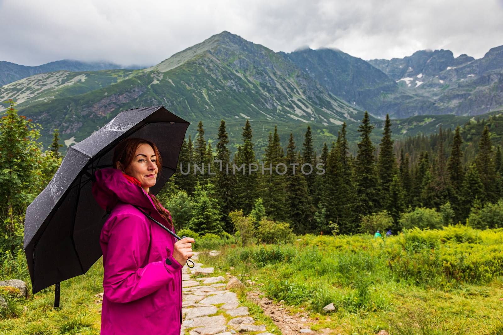 Beautiful mature woman with the umbrella in the mountain scenery