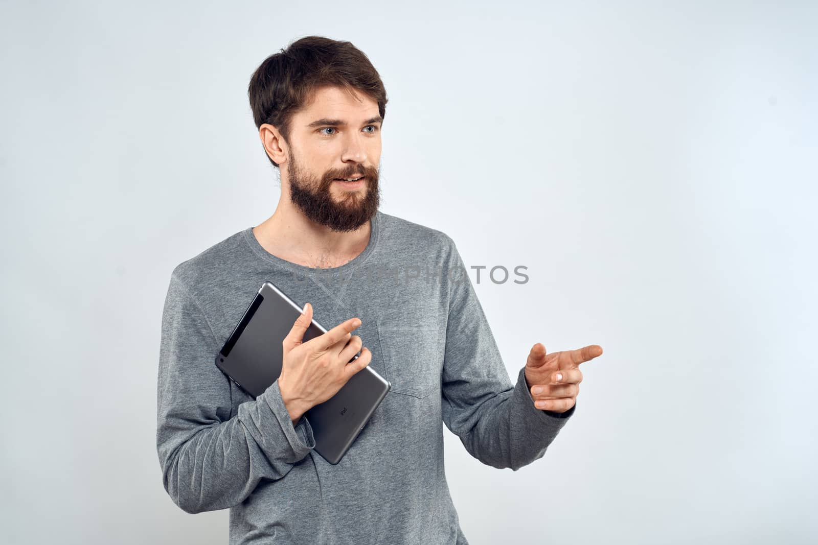 A man in a gray sweater a tablet in the hands of emotions Internet technology lifestyle light background. High quality photo