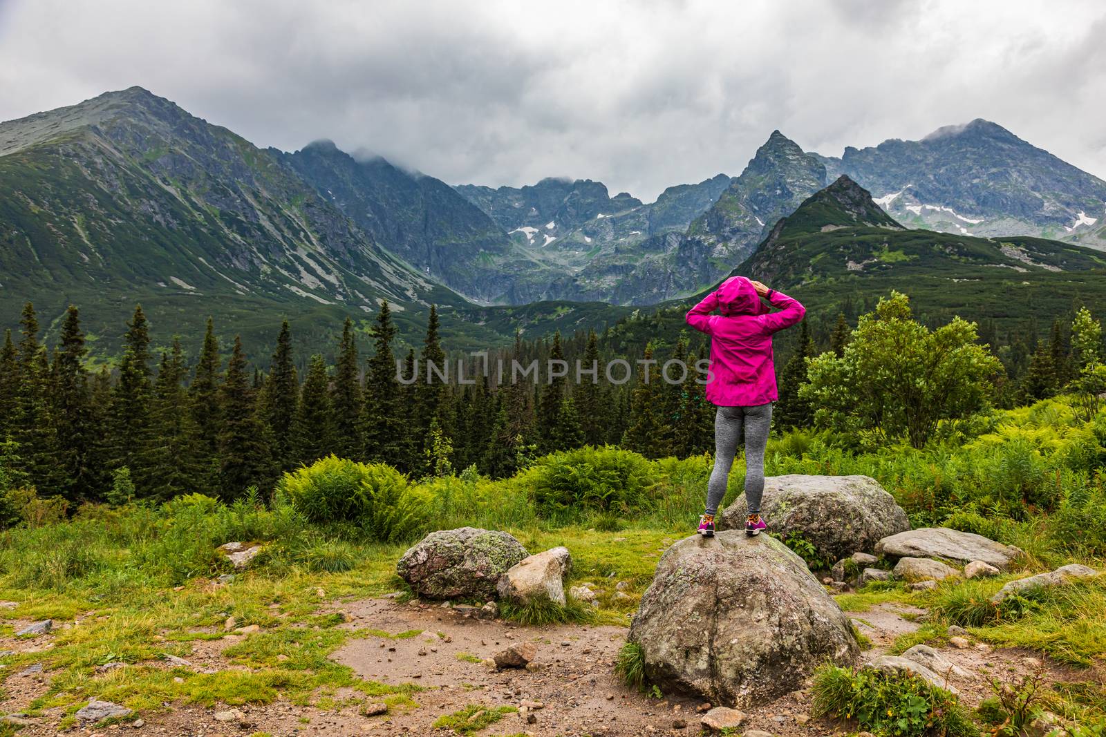woman in raincoat looking at the Tatra mountain panorama in the rain