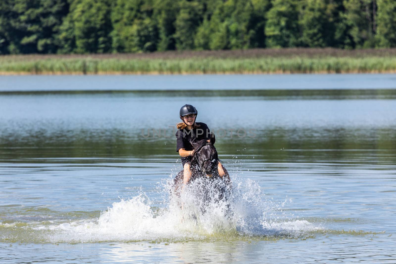 Horseback riding teenager girl galloping throug the water