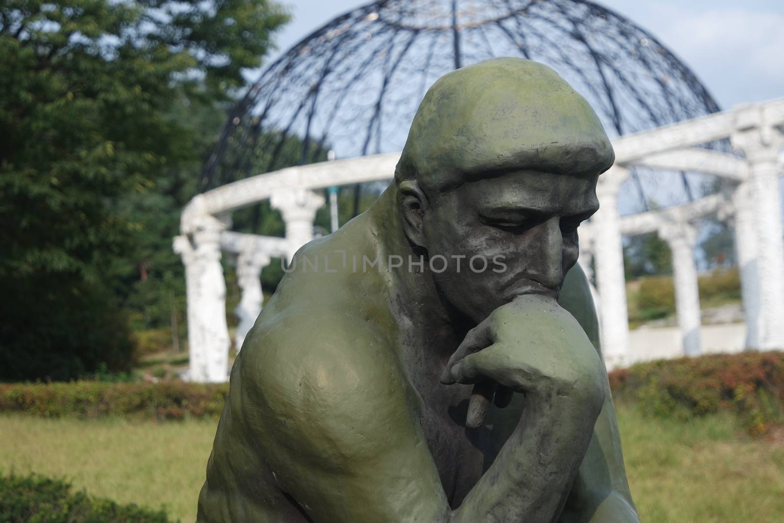 CHUNCHEON, SOUTH KOREA- JANUARY-10, 2019: Green statue of thinker Auguste Rodin, setting naked on a rock in a public park