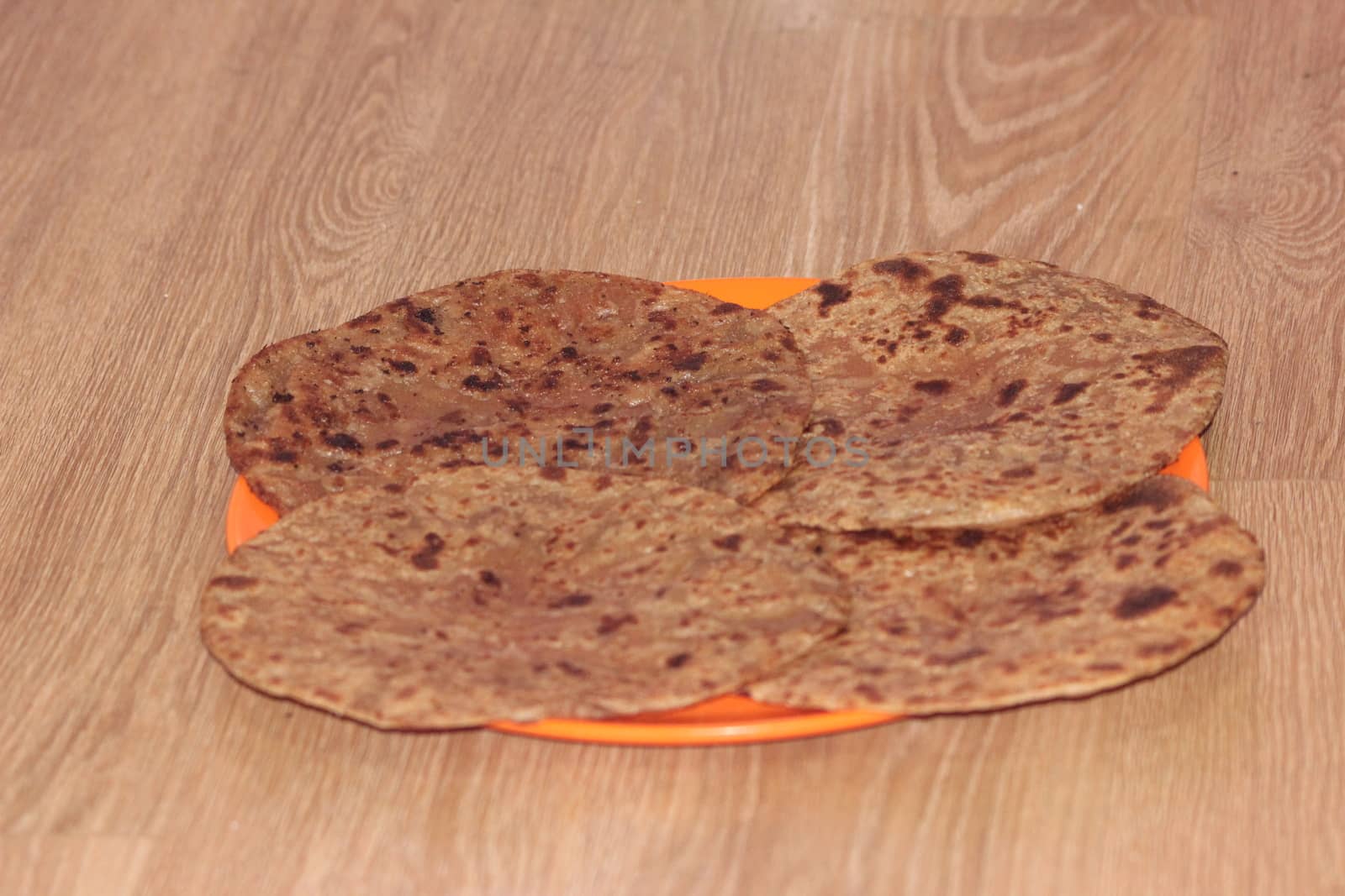 Traditional paratha - Macro closeup with selective focus of homemade oily bread or parotta on a plate on wooden floor. Chapati is traditional food of southeast Asia.