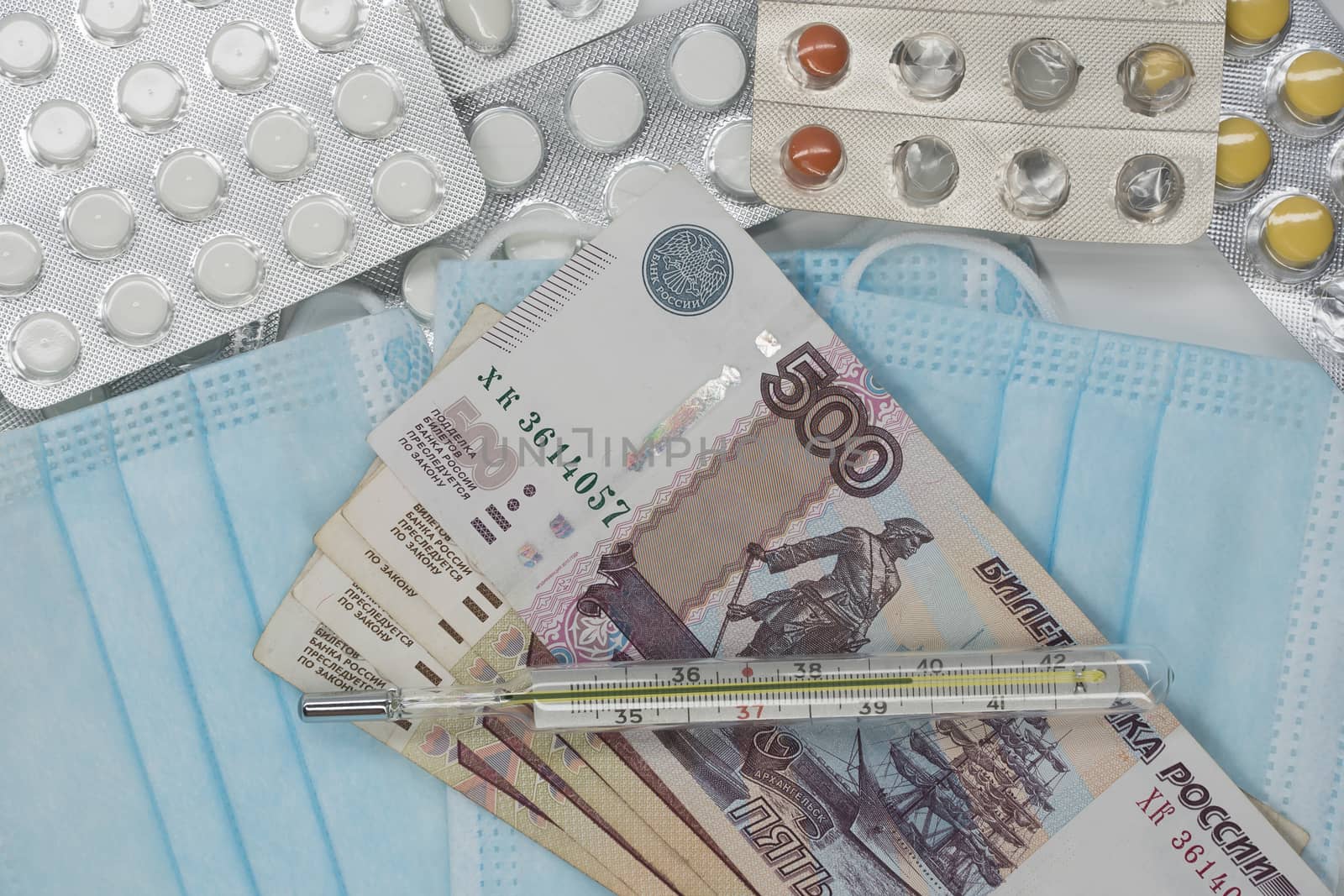 A thermometer, a pill, a medical mask and money in Rubles are on the table. Increase in prices for medicines in Russia in Rubles. Russia is on quarantine because of the epidemic of the coronavirus