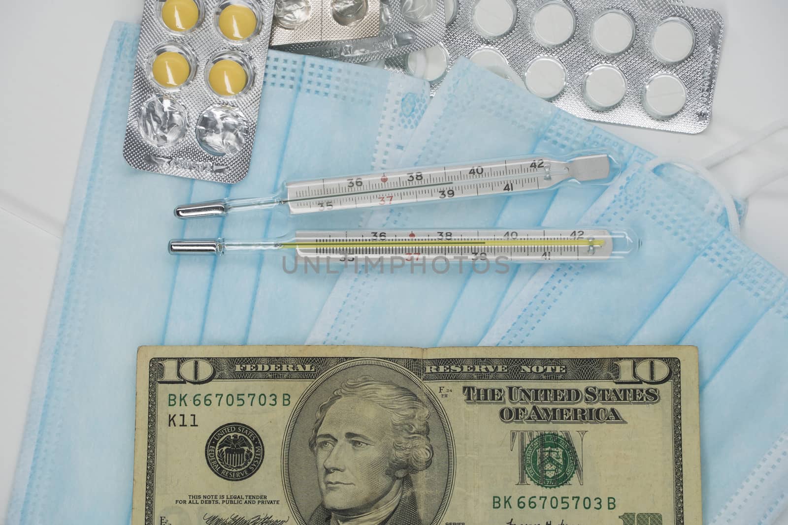 On the table is a thermometer, a pill, a medical mask, and money in dollars. The growth of prices for medicines in America in dollars.The United States is under quarantine of the epidemic coronavirus