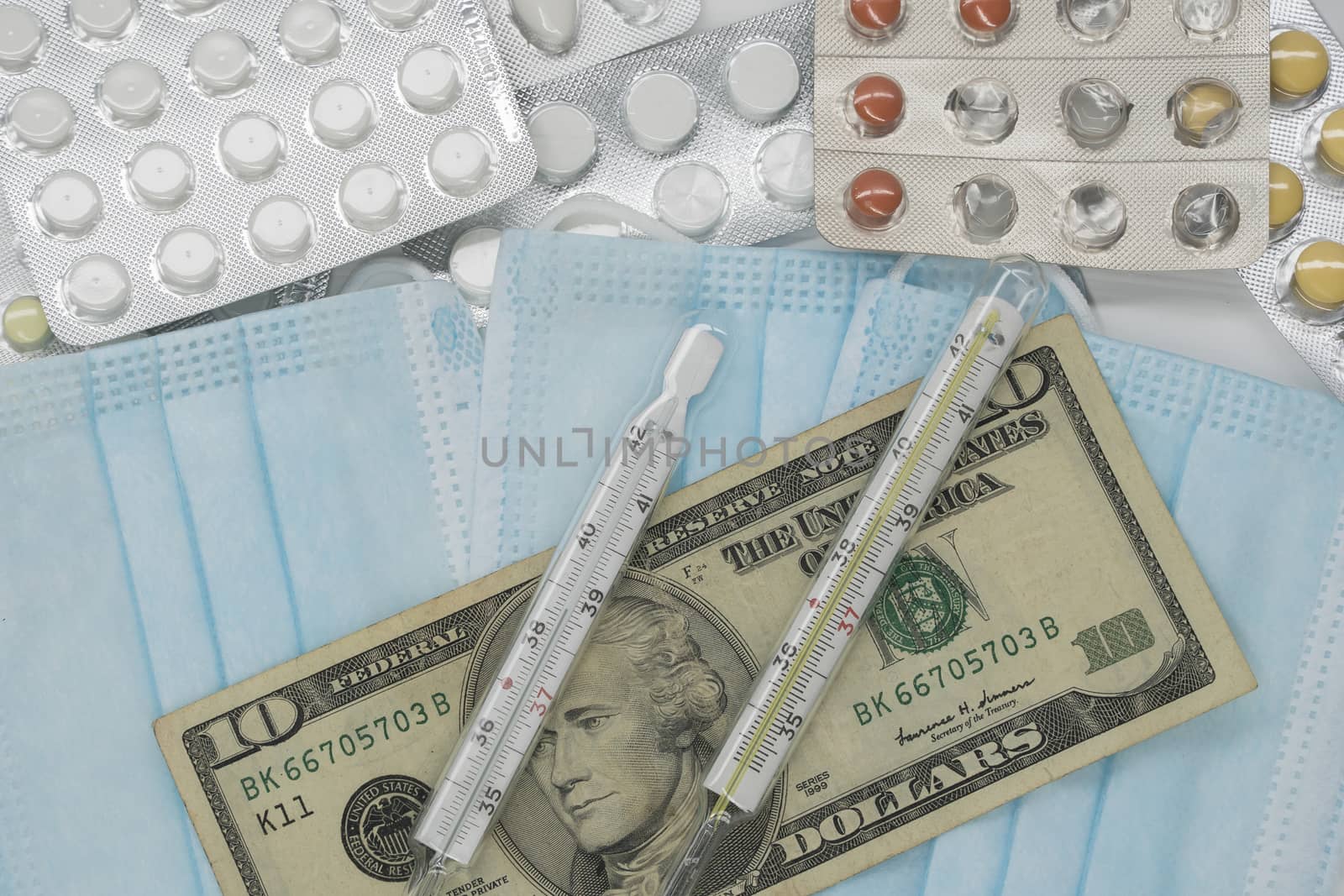 On the table is a thermometer, a pill, a medical mask, and money in dollars. The growth of prices for medicines in America in dollars.The United States is under quarantine of the epidemic coronavirus