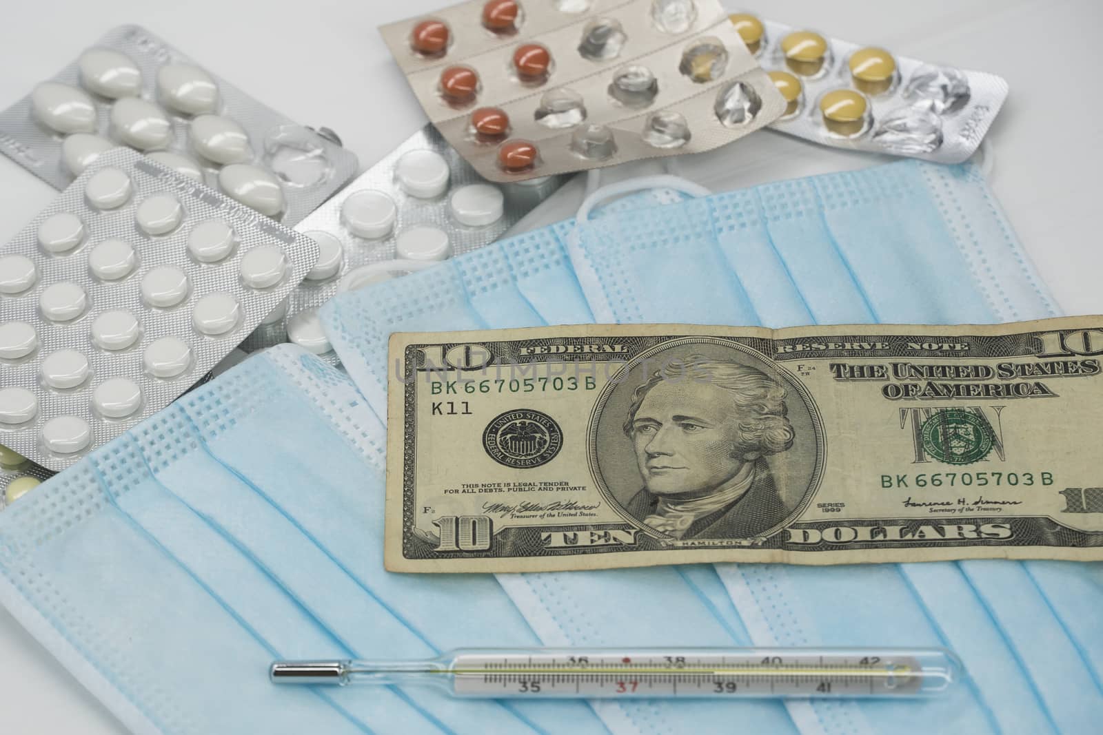 On the table is a thermometer, a pill, a medical mask, and money in dollars. The growth of prices for medicines in America in dollars.The United States is under quarantine of the epidemic coronavirus