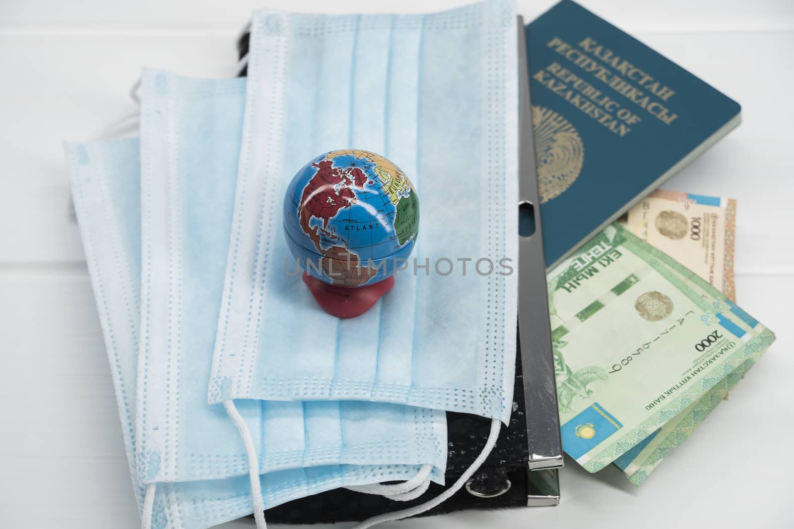 Quarantine in Kazakhstan. Tenge money with medical face masks, a globe, a card and a passport are on the table. The closure of borders and travel in Kazakhstan.