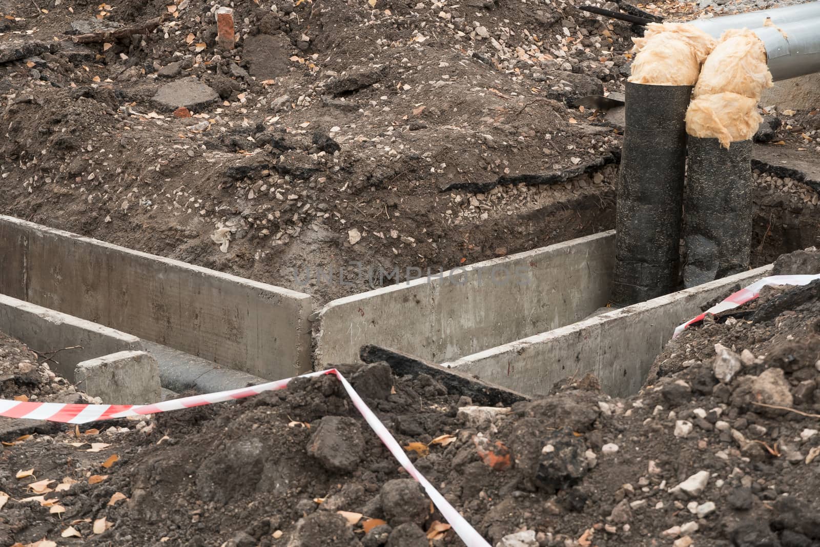 Repair of sewer pipes, water supply or drainage system. Underground to operate the equipment. Thick water pipes lie in a concrete box in a dug hole in the ground, preparing for the heating season