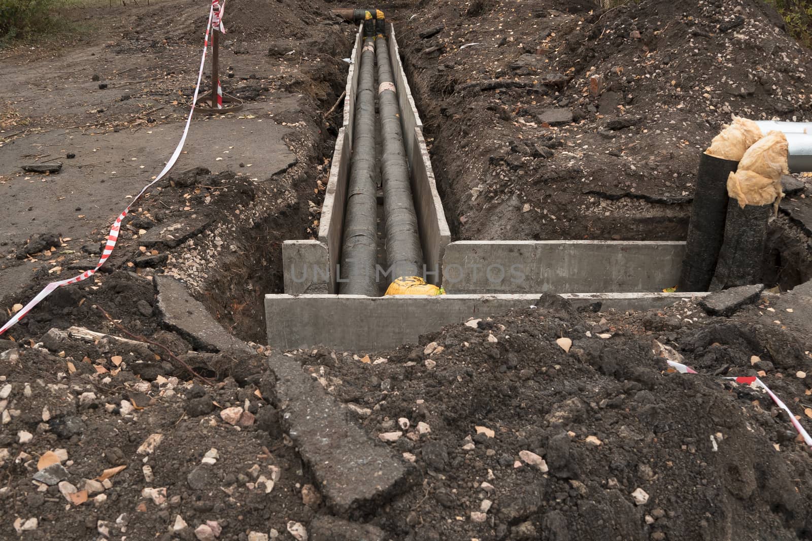 Repair of sewer pipes, water supply or drainage system. Underground to operate the equipment. Thick water pipes lie in a concrete box in a dug hole in the ground, preparing for the heating season