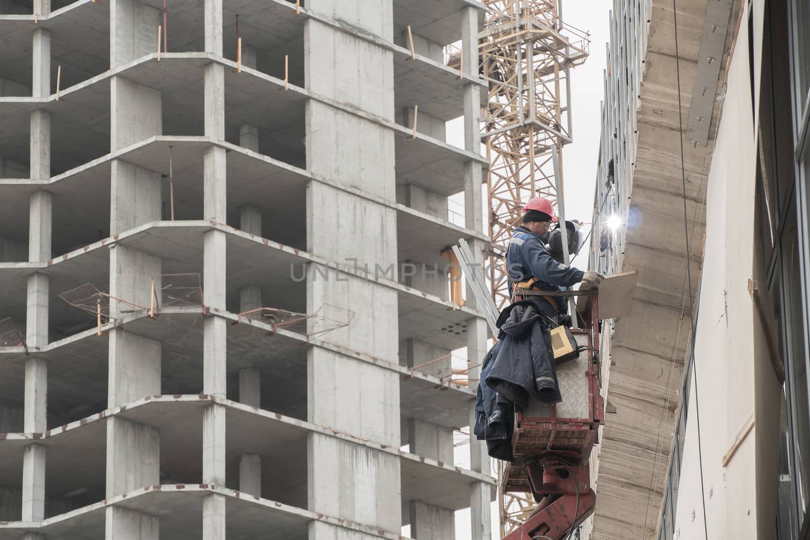 Moscow,Russia 10.07.2020:A construction worker who works as a welder, builds or repairs the facade of a building or structure.Construction and repair work on the street outside.A welder welds a metal