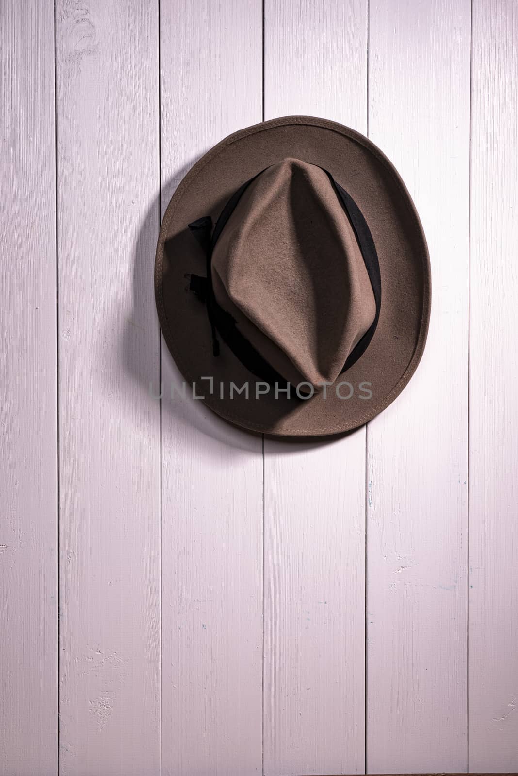 an old hat hanging on a white wooden wall