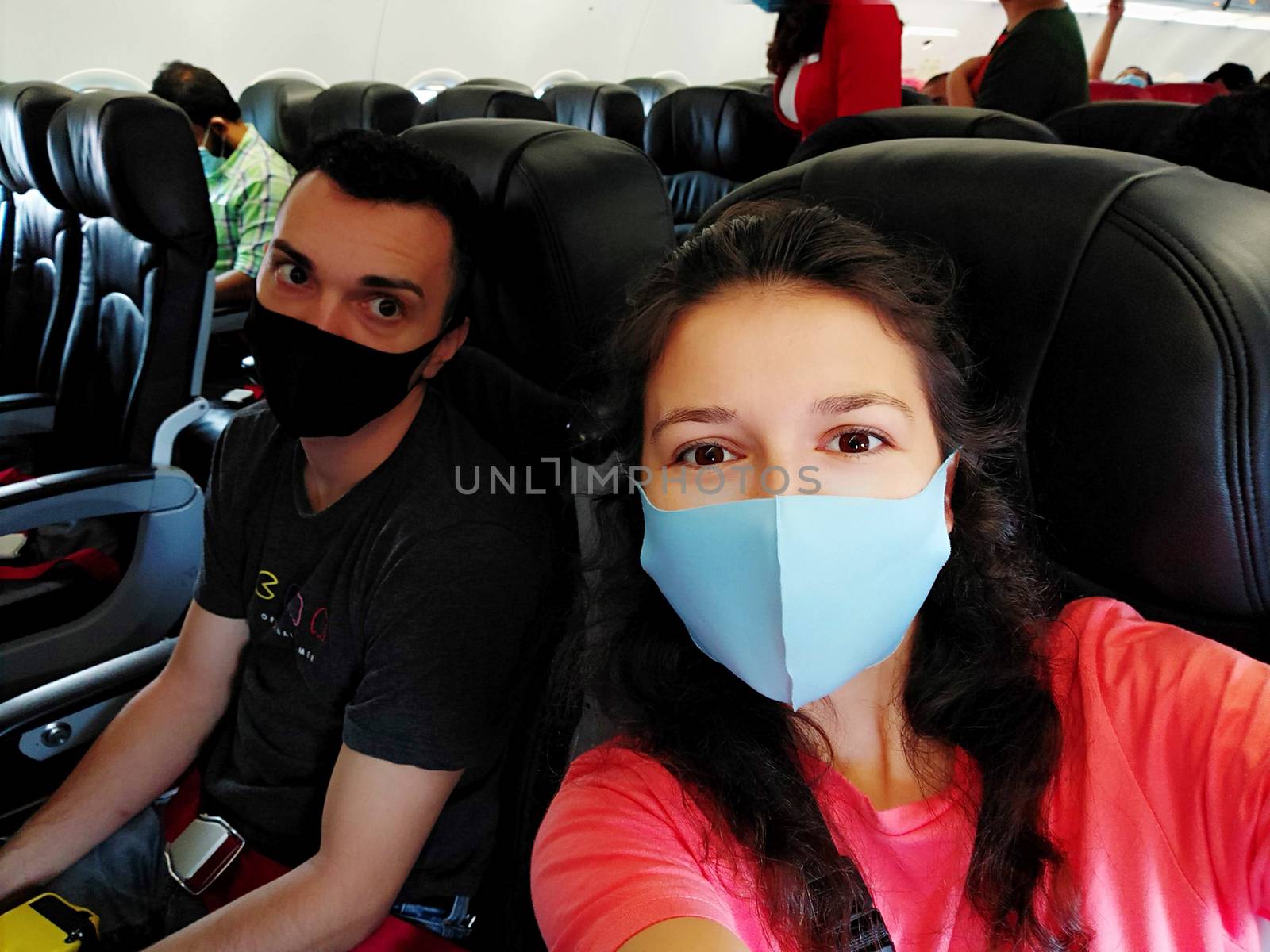 couple of travelers wearing masks on their faces in the cabin. Flights under the new rules of the coronavirus pandemic by Try_my_best