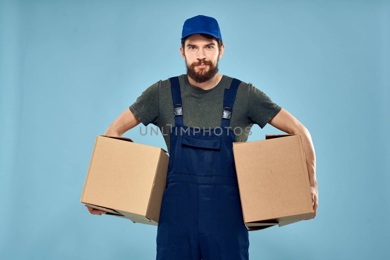 working man boxes in hands delivery service packaging lifestyle blue background. High quality photo