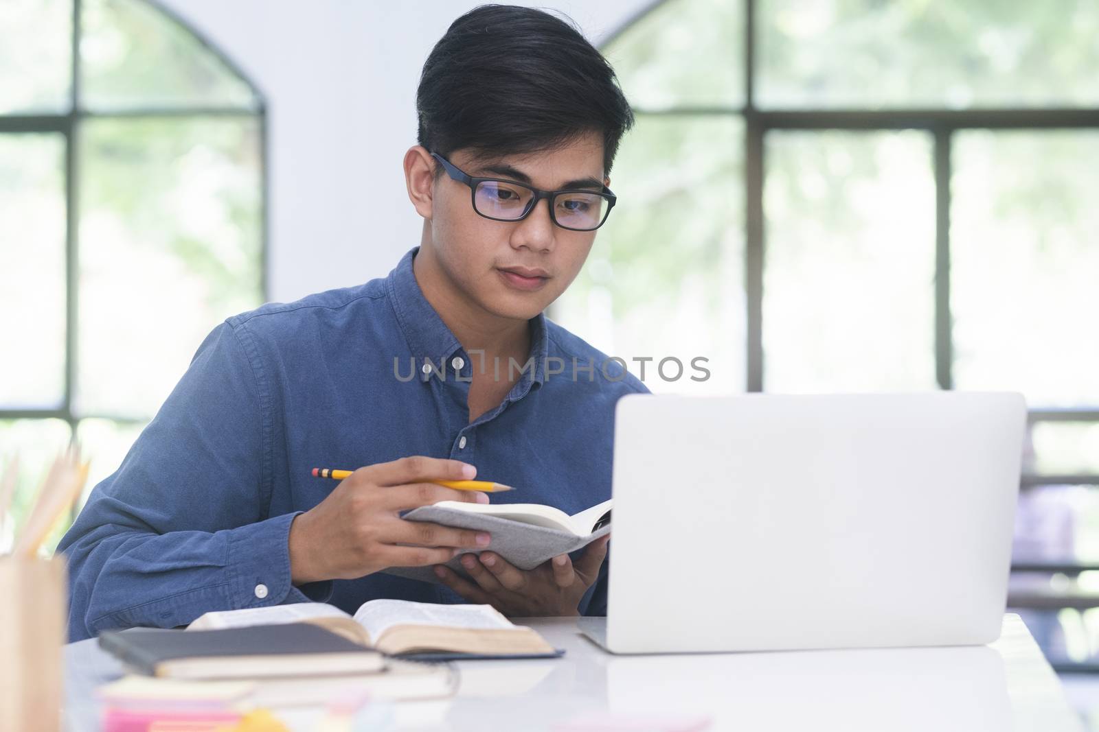 Young collage student using computer and mobile device studying online. Education and online learning.
