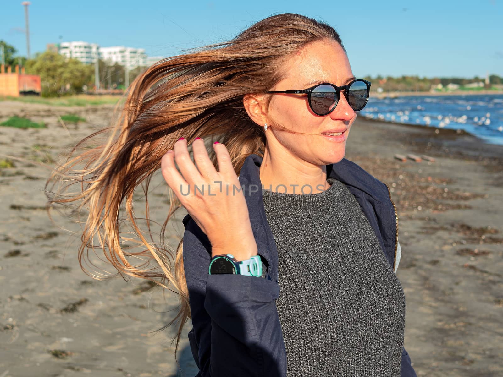 Pretty young girl ashore the Baltic sea. Young woman with long hair and dark coat in nature. autumn beach of the Baltic Sea. Blue sea on the backgroun. Copy space