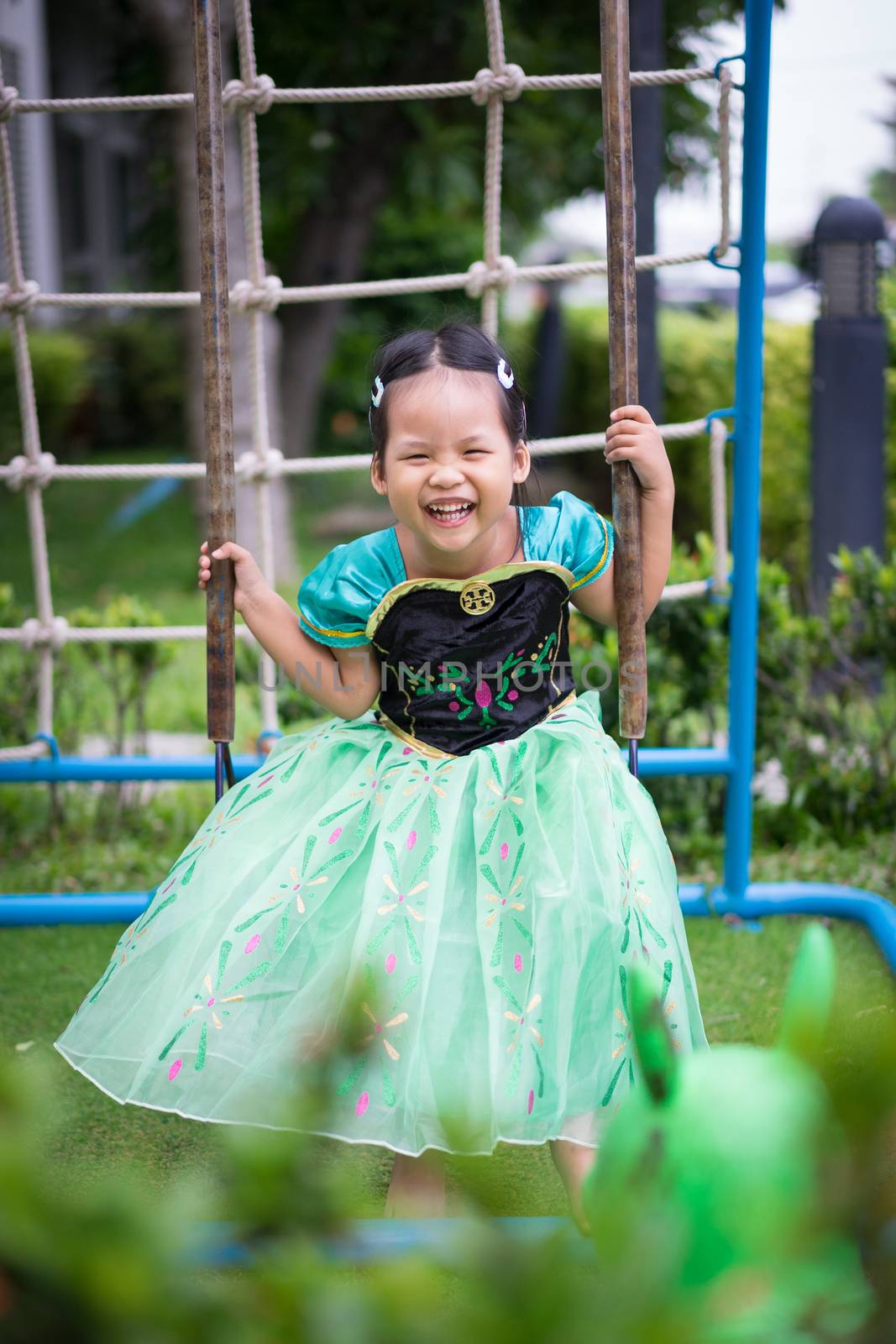 Portrait of cute smiling little girl in princess dress playing in children playground