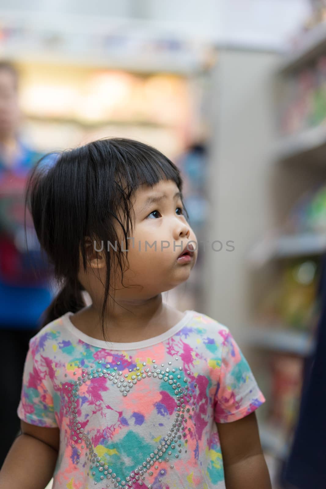 little girl walking in minimart and look up product for shopping
