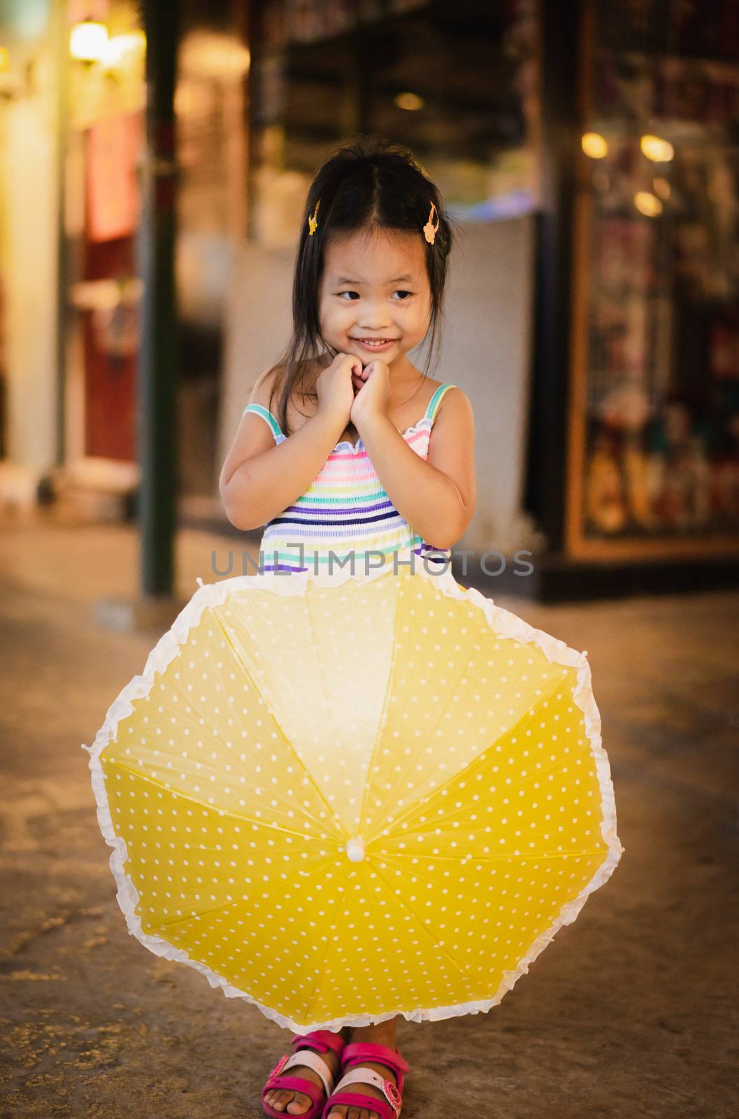 little girl with umbrella in the market on raining day