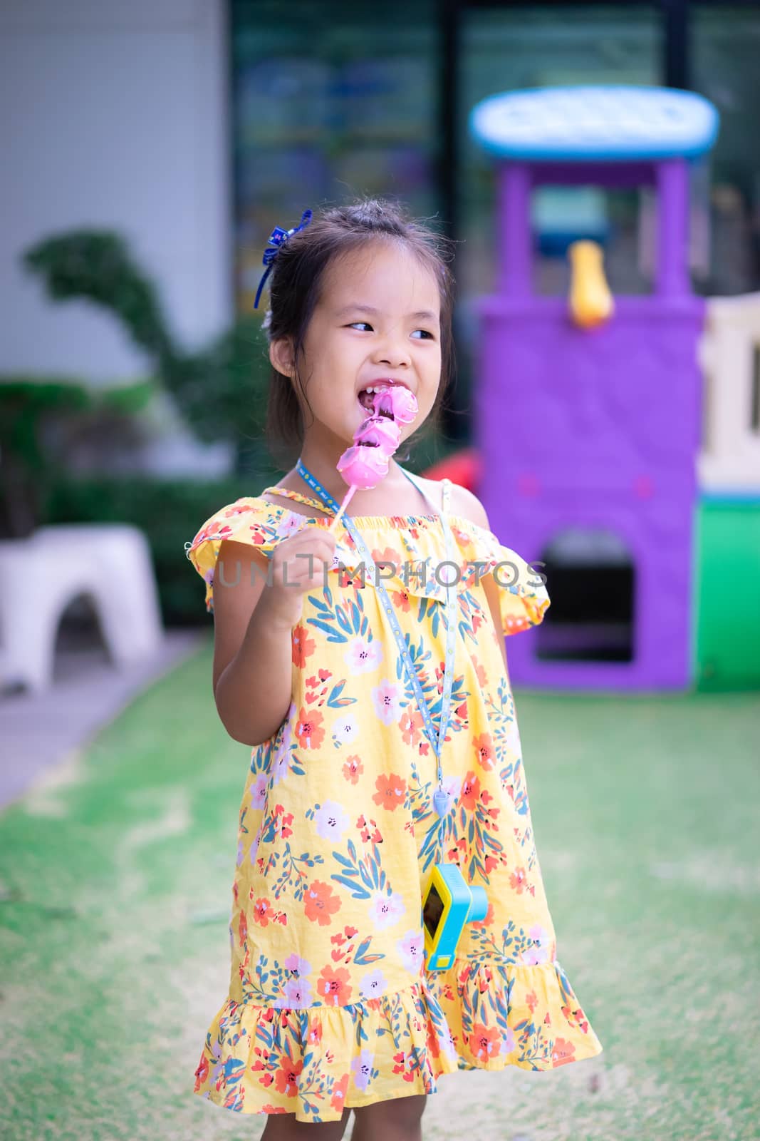 Portrait of little asian girl holding and eating donuts outdoor by domonite