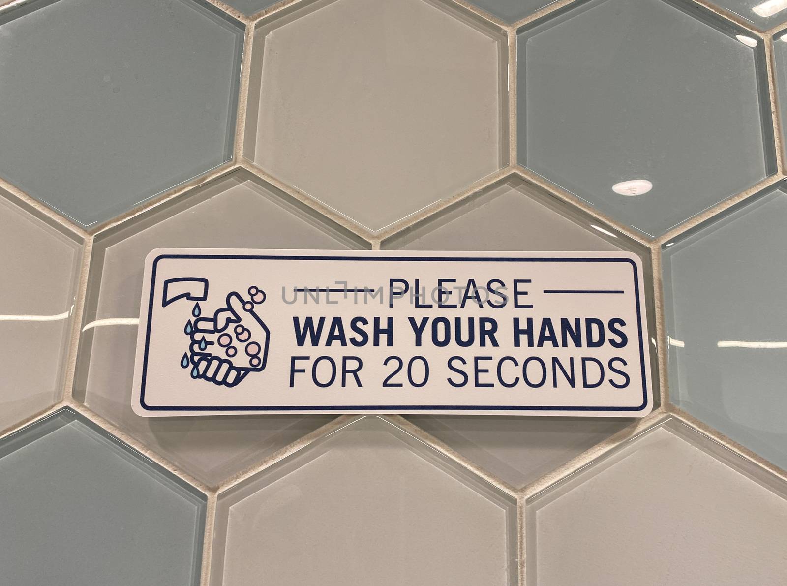 A sign in a public restroom that tells people to please wash your hands for 20 seconds due to the coronavirus pandemic.